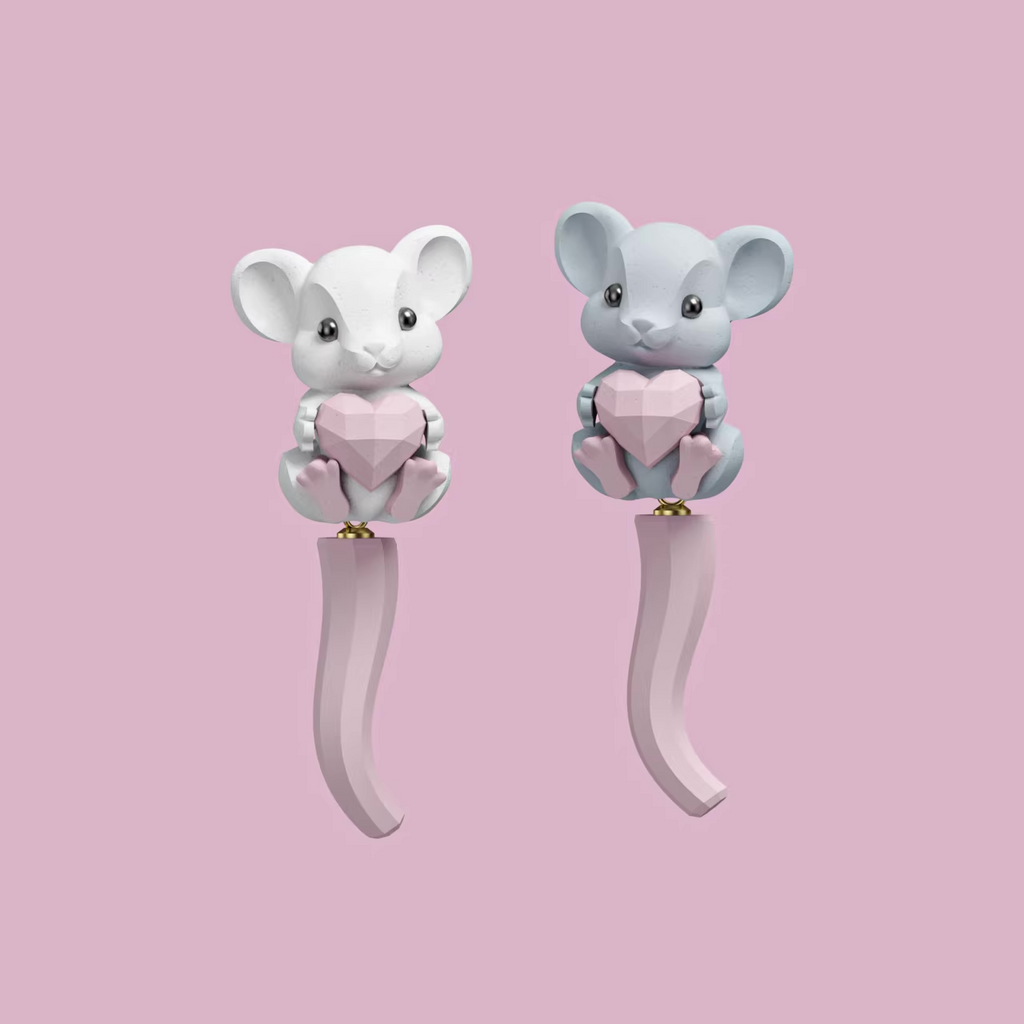 Cute pastel mouse earrings holding a pink heart, featuring a soft sculpted tail and whimsical character design on a pastel pink background.