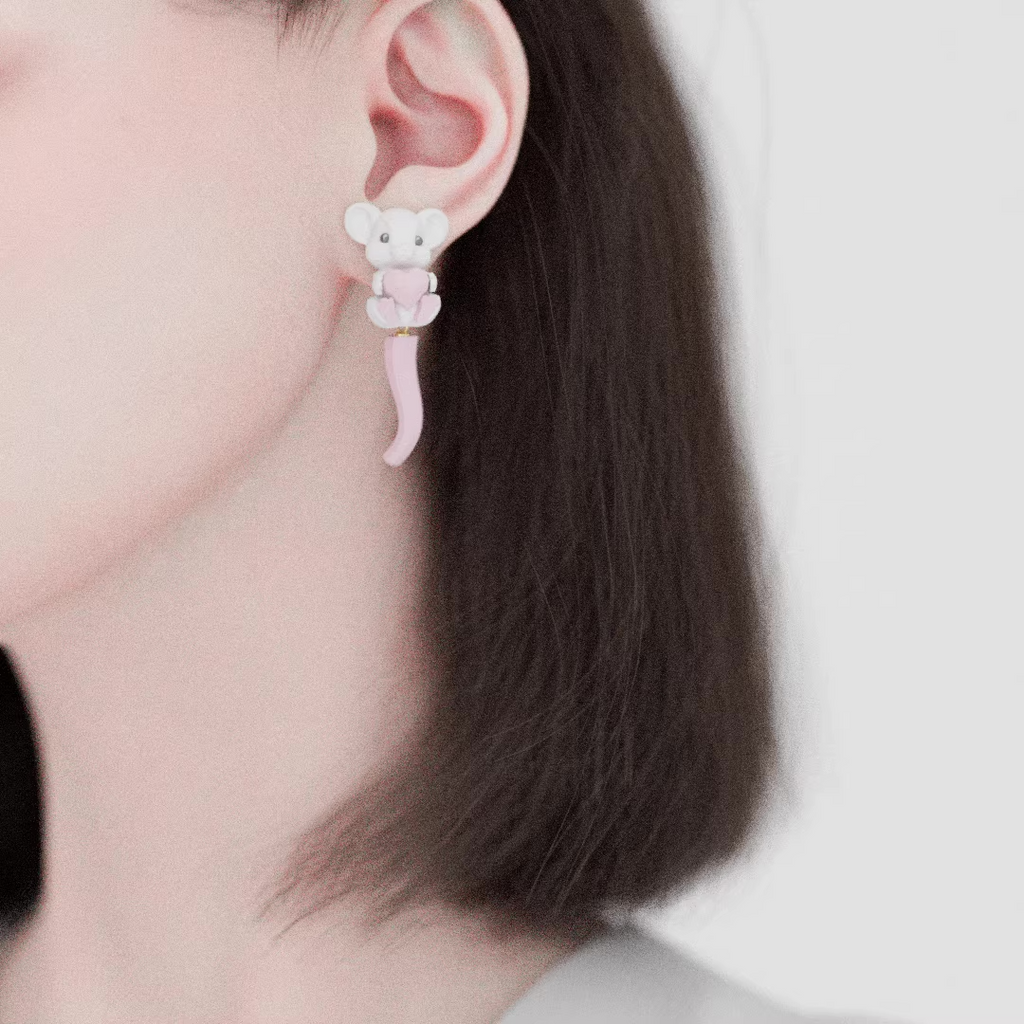 Cute pastel mouse earrings holding a pink heart, featuring a soft sculpted tail and whimsical character design on a pastel pink background.