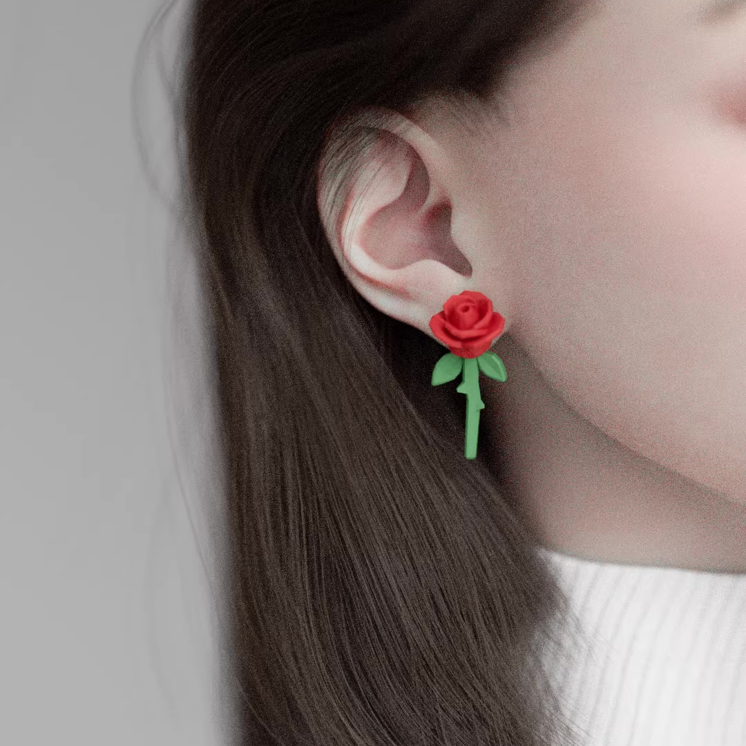 Handmade rose stud earrings featuring sculpted acrylic roses with green stems, lightweight pastel floral jewelry on a soft background.